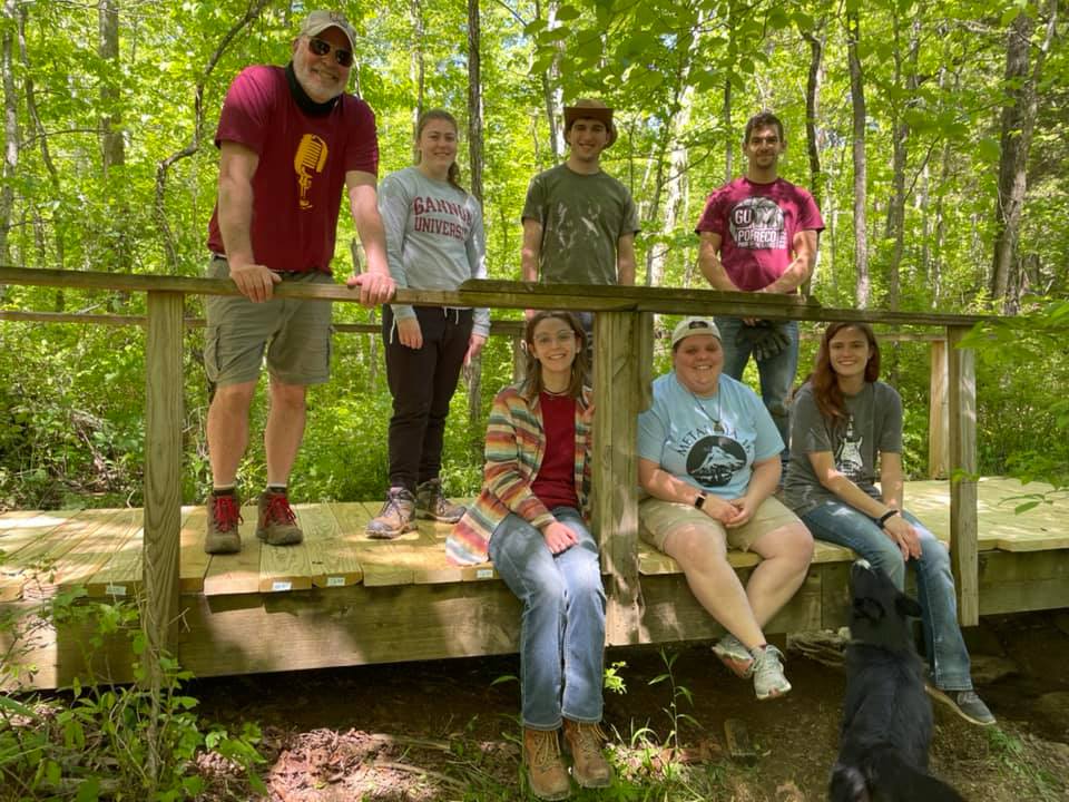 Gannon University Service Learning students sitting on the wooden footbridge they helped build in the Berea College forest